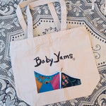 Tote bag with 'Baby Yams' logo on a patterned fabric background
