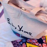 canvas bag with 'Baby Yams' branding on a colorful background with zipper