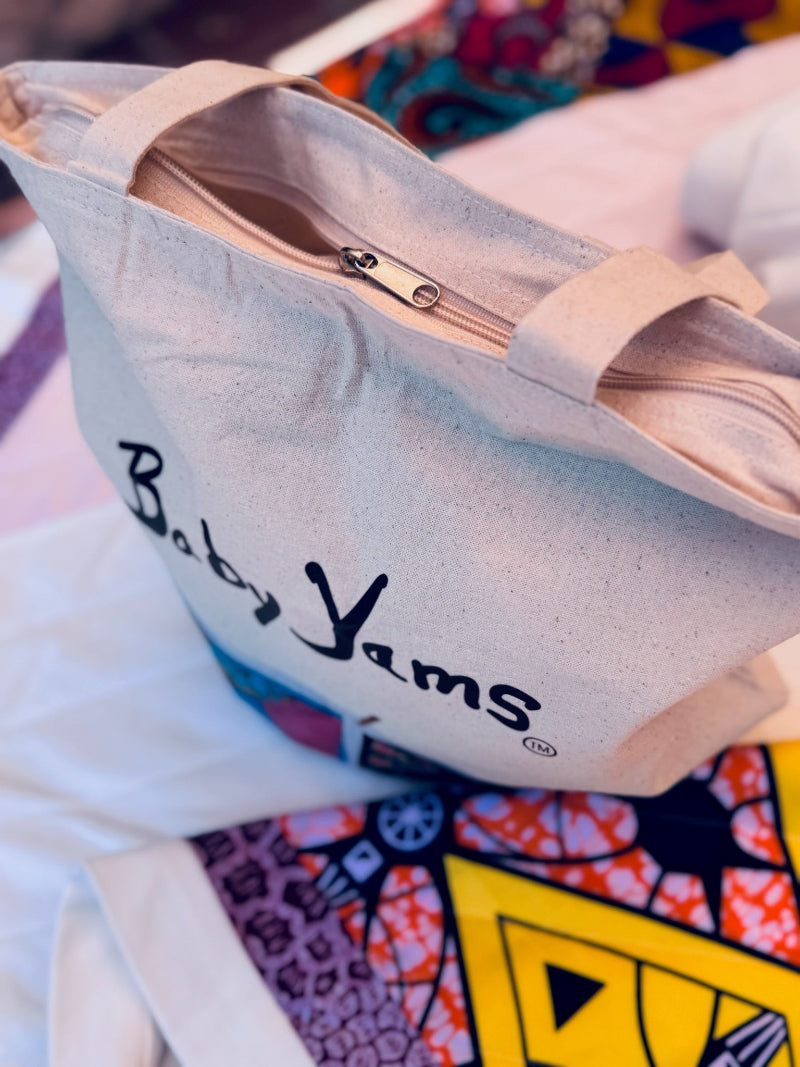 canvas bag with 'Baby Yams' branding on a colorful background with zipper